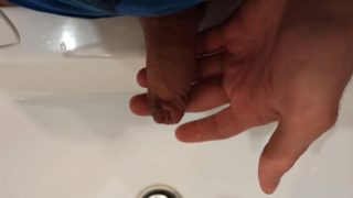 The boy is pissing into the washstand.